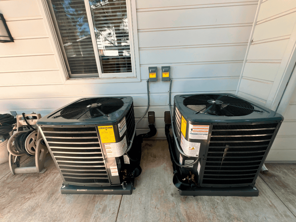 Two HVAC units outside a house for cooling and heating.